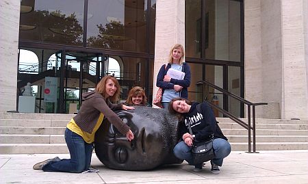 Four women pose with head sculpture outside Sheldon Museum of Art