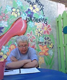 Jan Knispel reading her work on in front of a colorful mural