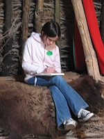 Maija Grinvalds sitting on a hay bale, writing